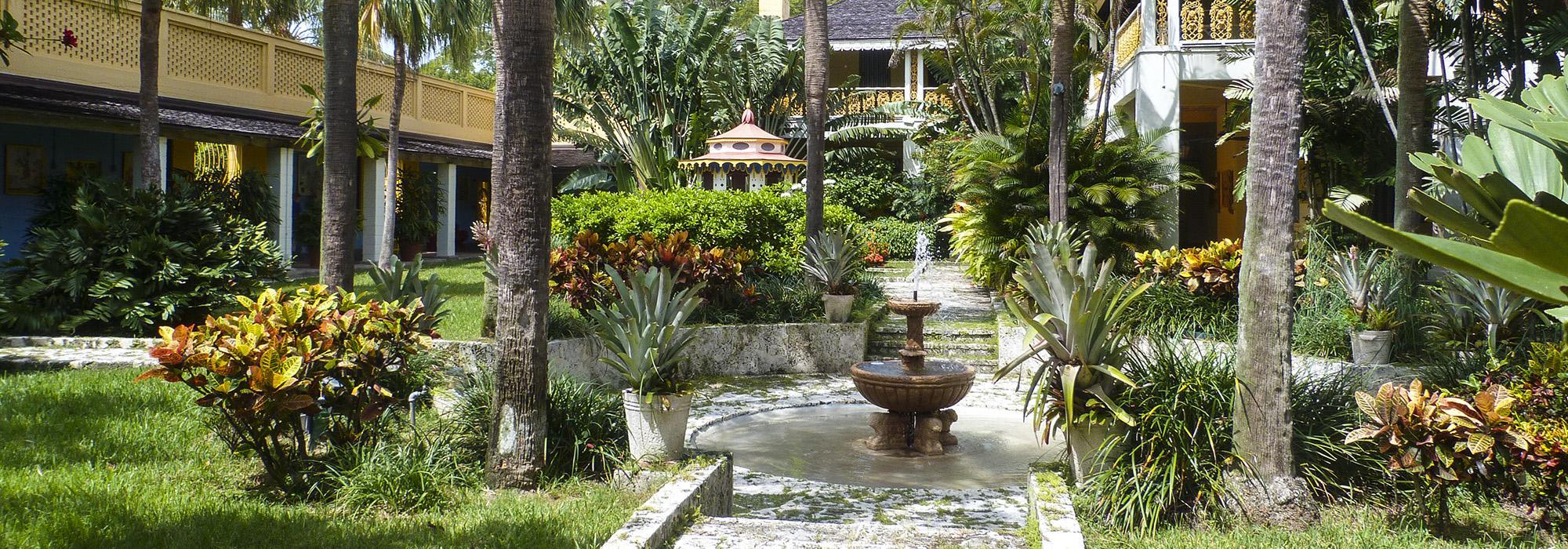Stone fountain surrounded by tropical palms and colorful foliage in a lush South Florida garden courtyard, a picturesque Miami wedding venue setting