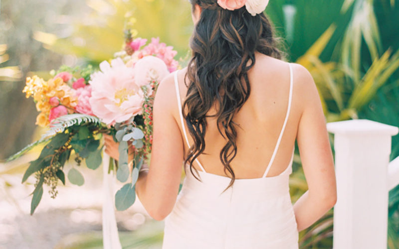  Pink garden rose, white ranunculus, eucalyptus and red hypericum berries were woven into the half-up bridal hairstyle