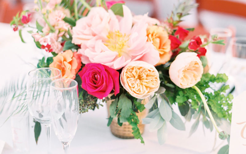 Vibrant wedding reception centerpieces included blush garden roses, pink peonies, dahlias, fuchsia roses, orange lisianthus, pink delphiniums, eucalyptus, greenery and red spray roses
