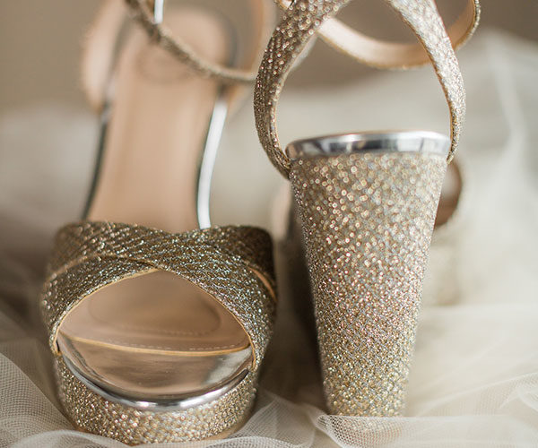 Neutral wedding shoes with a hint of metallic blush gold perfectly complement the purple wedding colors of the bridal bouquet