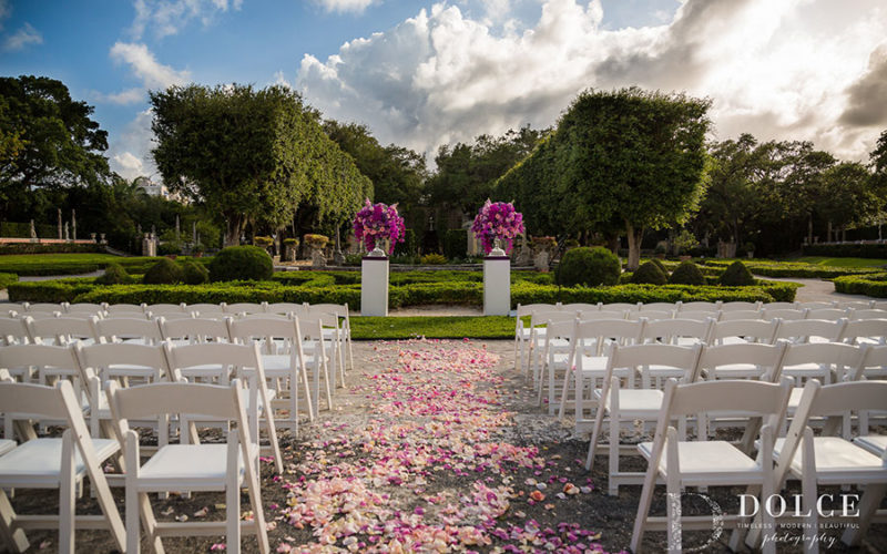 Ceremony decor | Vibrant pink, purple and ultra violet floral urns add a pop of color to this Vizcaya wedding ceremony set-up