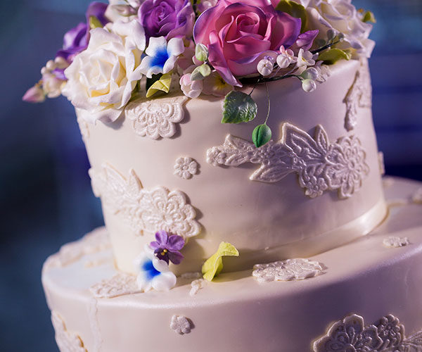 Wedding Colors 2018 | Delicate ultra violet and pink sugar flowers accent the ivory wedding cake
